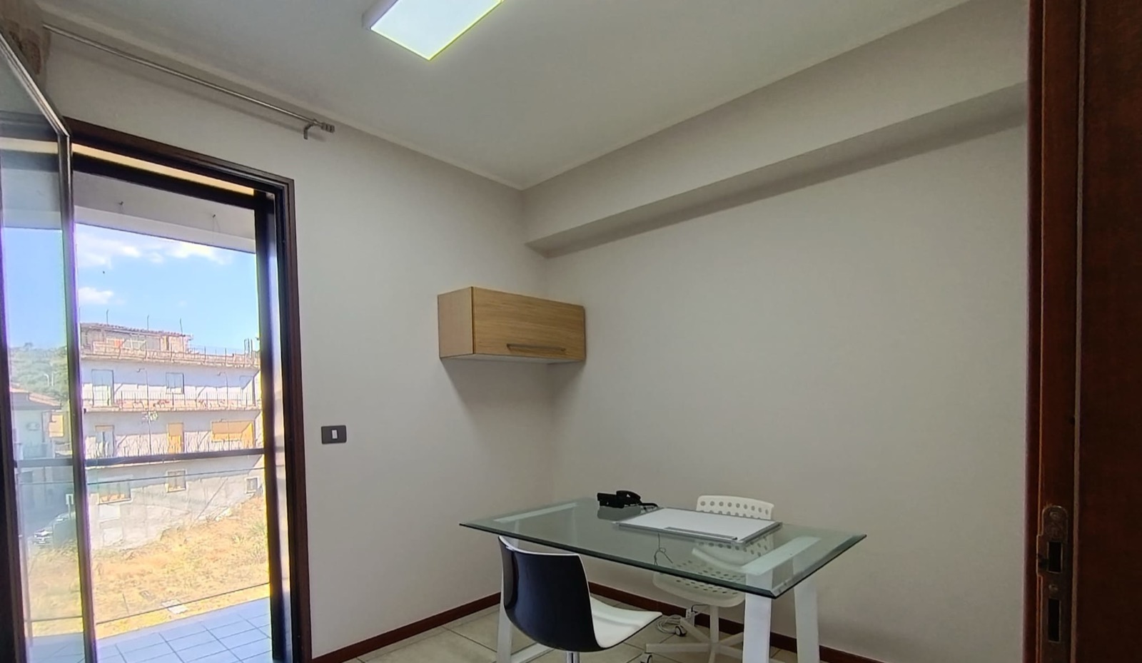 Ufficio con scrivania in vetro e portafinestra sul balcone